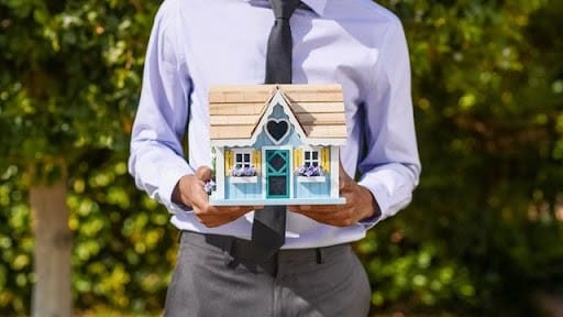 man holding a house made of cardboard