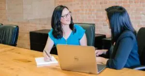 two women talking in front of a computer