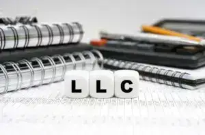 LLC spelled out on dice on top of spreadsheet beside notebooks