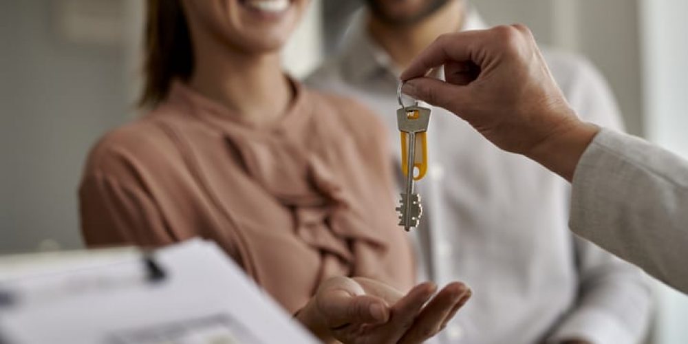 Close-up of real estate agent giving new house keys to a couple.