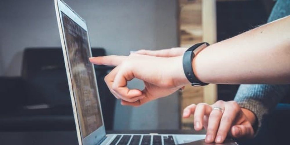 finger pointing to a laptop screen
